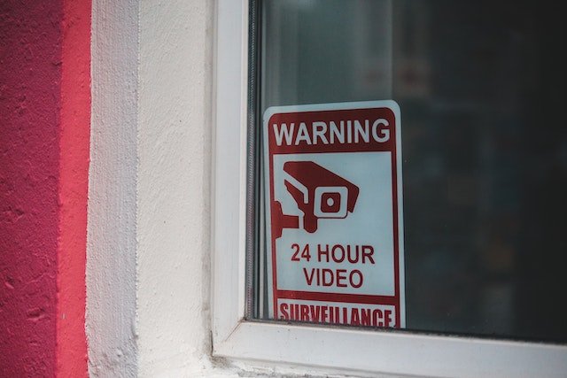 a sign in a window warning of 24 hours video surveillance