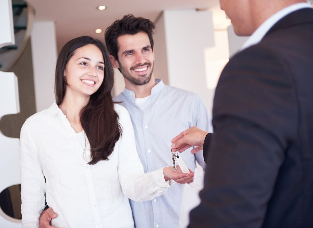 Cropped person handing a set of keys to a smiling couple