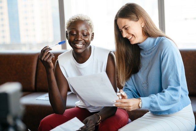 Two smiling people sitting together and reviewing a document